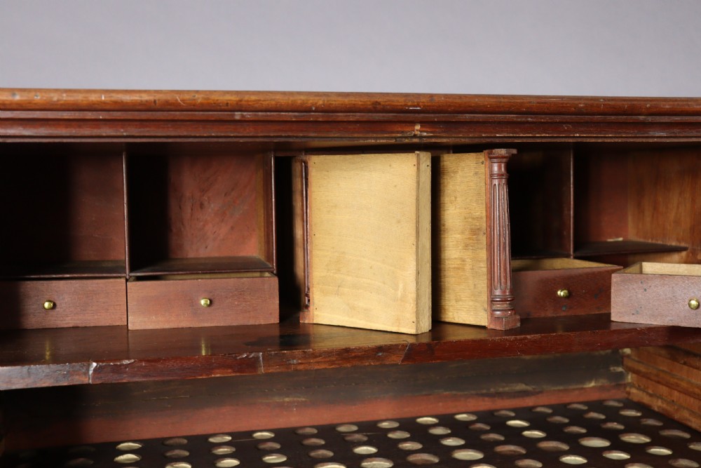 An eighteenth-century George II red walnut cabinet on a kneehole base with open doors revealing fitted internal drawers and pigeonholes above brass-handled drawers. View VII