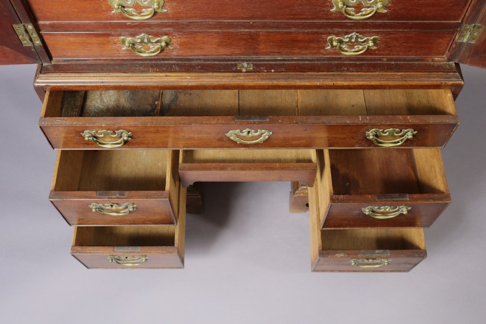 An eighteenth-century George II red walnut cabinet on a kneehole base with open doors revealing fitted internal drawers and pigeonholes above brass-handled drawers. View VIII