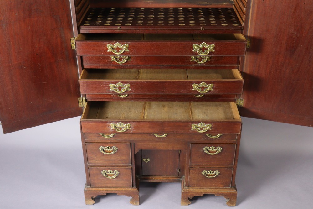 An eighteenth-century George II red walnut cabinet on a kneehole base with open doors revealing fitted internal drawers and pigeonholes above brass-handled drawers. View IX
