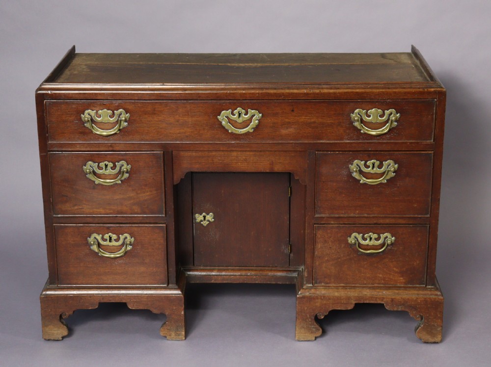An eighteenth-century George II red walnut cabinet on a kneehole base with open doors revealing fitted internal drawers and pigeonholes above brass-handled drawers. View XII