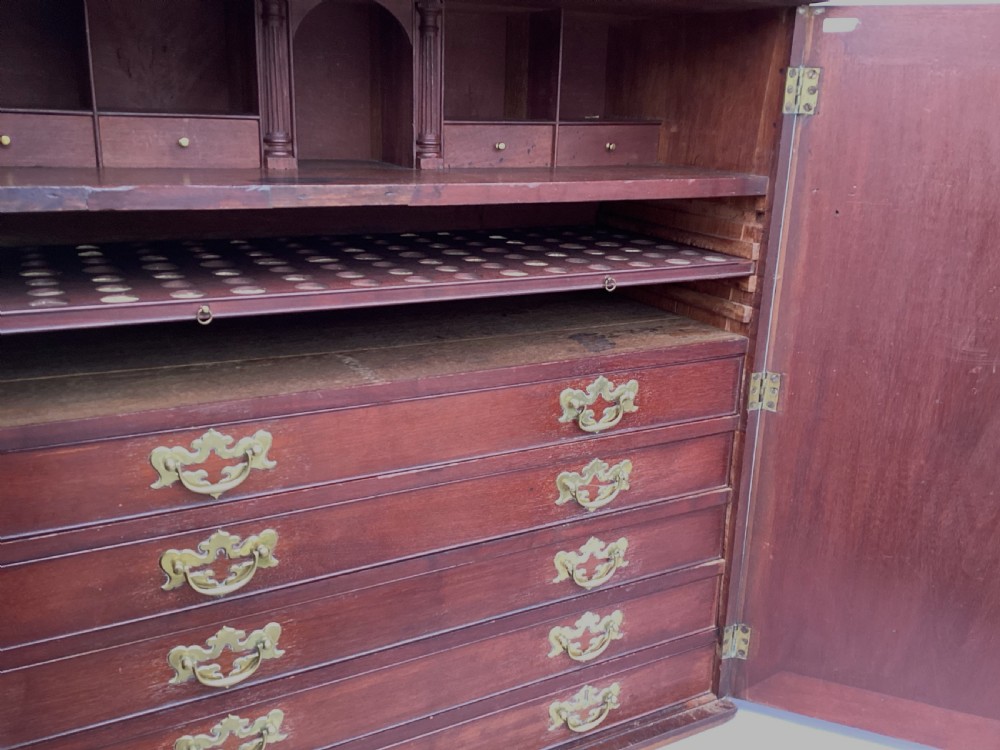 An eighteenth-century George II red walnut cabinet on a kneehole base with open doors revealing fitted internal drawers and pigeonholes above brass-handled drawers. View XV