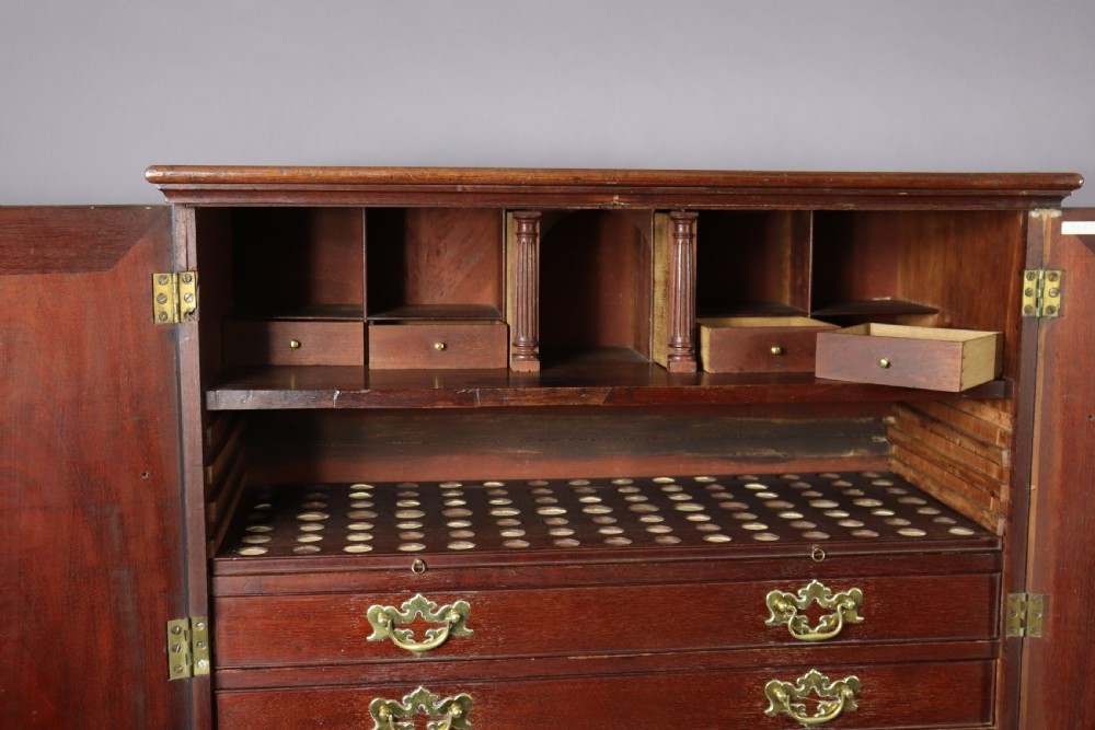 An eighteenth-century George II red walnut cabinet on a kneehole base with open doors revealing fitted internal drawers and pigeonholes above brass-handled drawers. View XVI