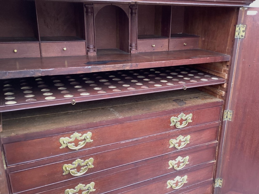 An eighteenth-century George II red walnut cabinet on a kneehole base with open doors revealing fitted internal drawers and pigeonholes above brass-handled drawers. View XIX