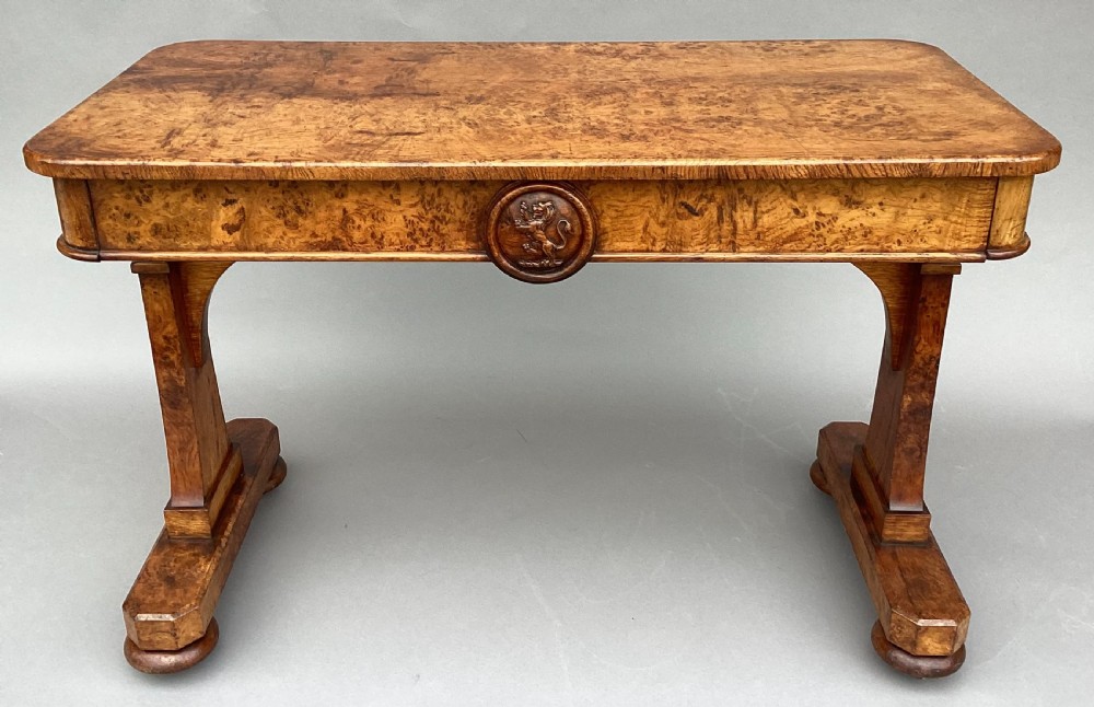 A mid-19th-century centre table crafted from figured burr and pollard oak, featuring rounded corners, a central carved medallion on the frieze, and twin end-standard supports on sledge bases. View V