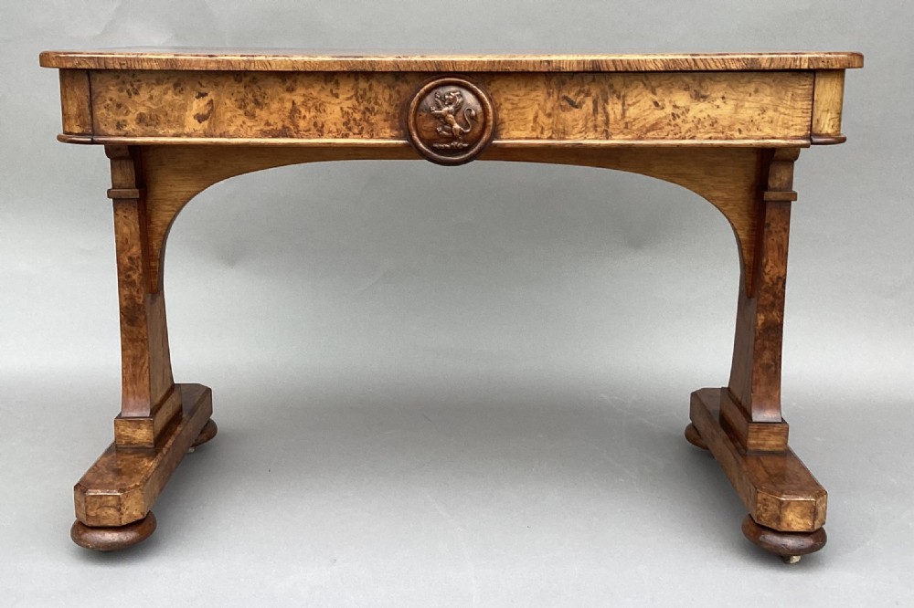 A mid-19th-century centre table crafted from figured burr and pollard oak, featuring rounded corners, a central carved medallion on the frieze, and twin end-standard supports on sledge bases. View XIII