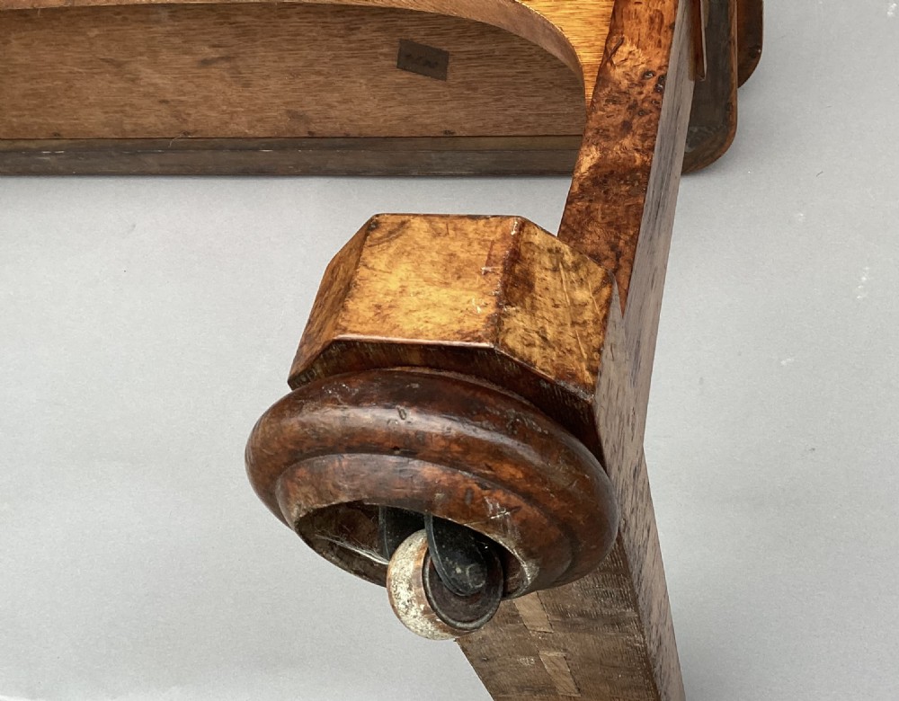 A mid-19th-century centre table crafted from figured burr and pollard oak, featuring rounded corners, a central carved medallion on the frieze, and twin end-standard supports on sledge bases. View XXI