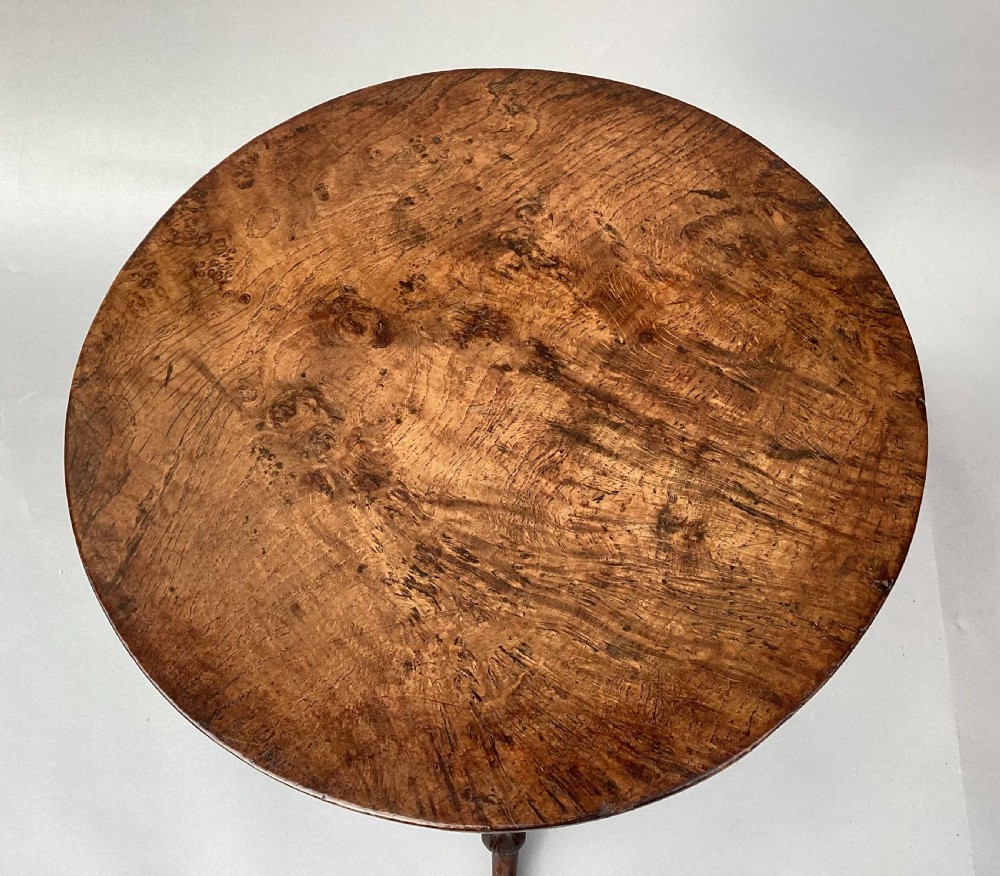 An 18th-century Irish Georgian burr oak tripod wine table featuring a circular top, turned central pedestal, and three cabriole legs terminating in pad feet. View XI