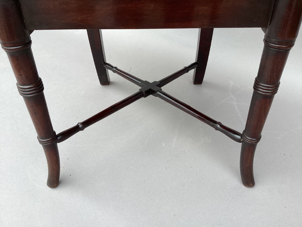 A pair of George III mahogany hall chairs with shield-shaped backs featuring circular brass inlays, dished wooden seats, and turned legs. View XV