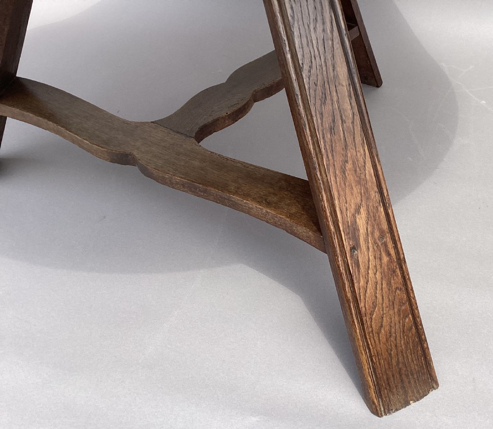 A circular 19th-century solid oak table with a warm brown grain finish, supported by a splayed base featuring dark iron strapwork. View XI