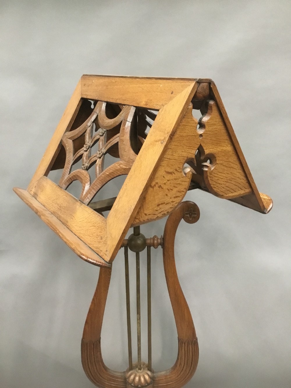 A 19th-century carved oak duet music stand featuring a dual-sided fretwork desk supported by a lyre-shaped stem and a tiered moulded square base. View V