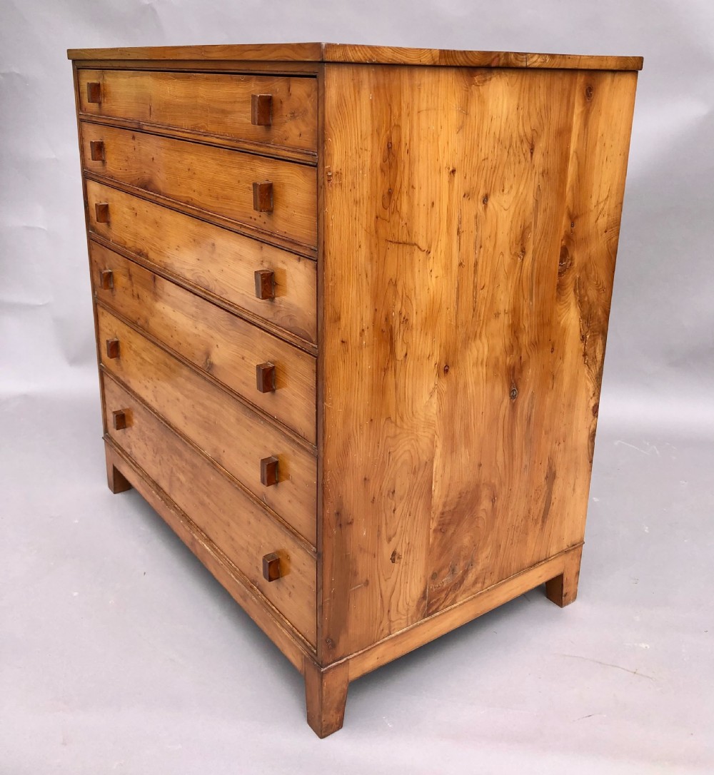 An Arts and Crafts solid yew wood chest featuring six graduated drawers with simple square wooden pulls. View V