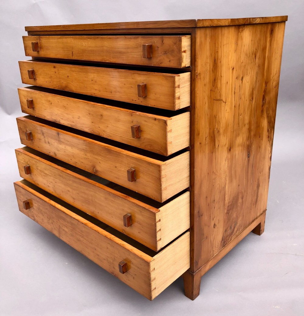 An Arts and Crafts solid yew wood chest featuring six graduated drawers with simple square wooden pulls. View XVI