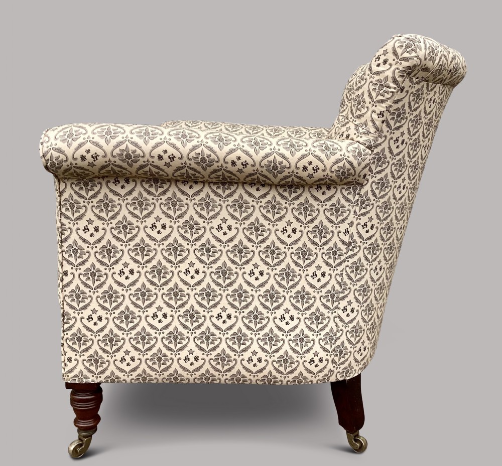 A Victorian Howard and Sons Woodstock armchair upholstered in patterned cream fabric with turned timber legs and brass castors. View IX