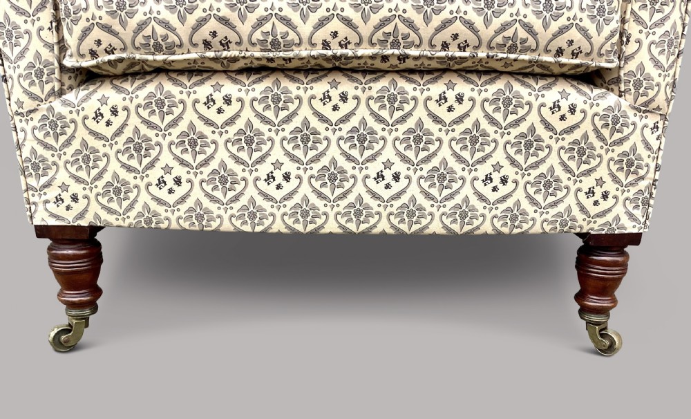 A Victorian Howard and Sons Woodstock armchair upholstered in patterned cream fabric with turned timber legs and brass castors. View XIII