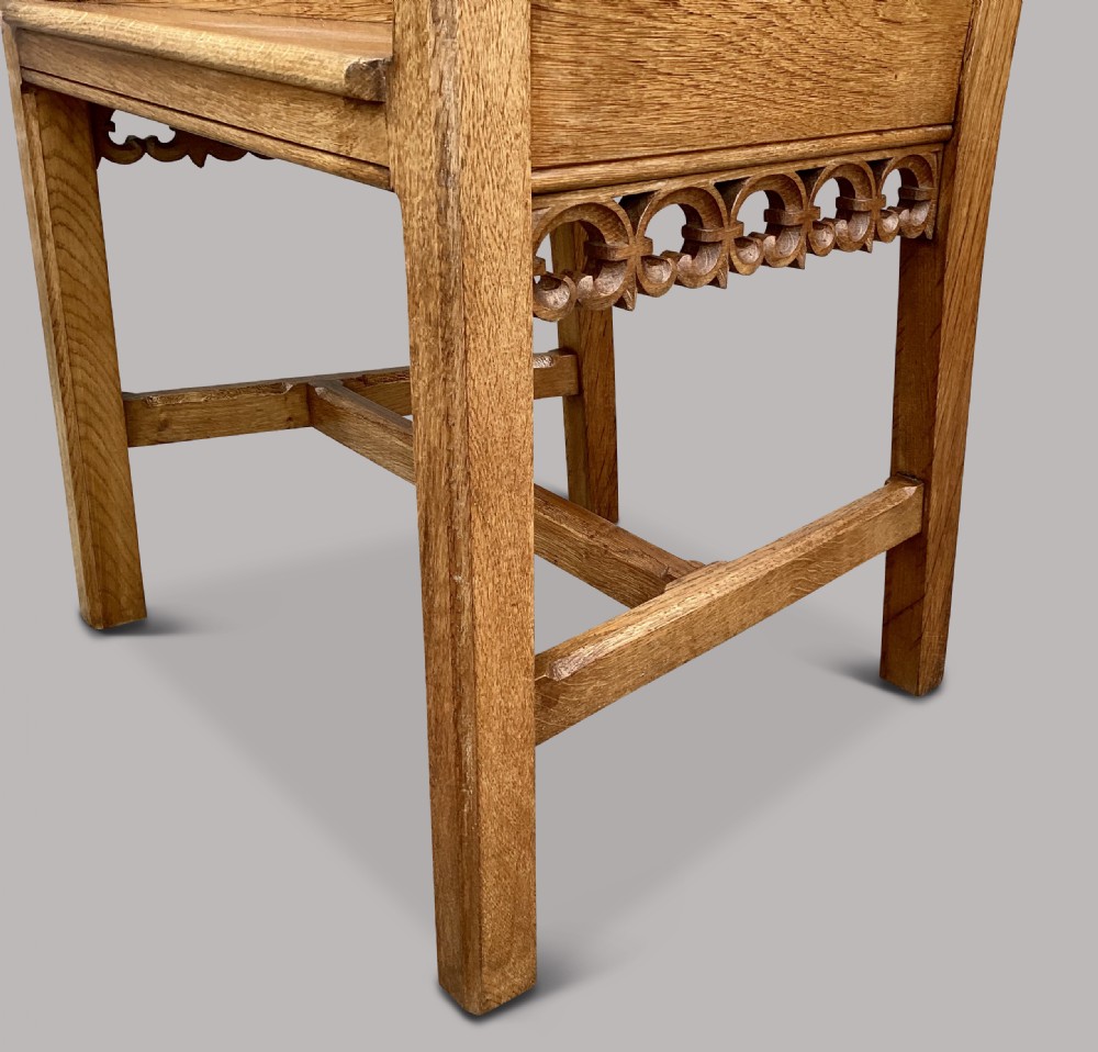 A pair of 19th-century golden oak Gothic Revival armchairs featuring high panelled backrests, shaped arms with spherical terminals, and solid oak seats. View IV