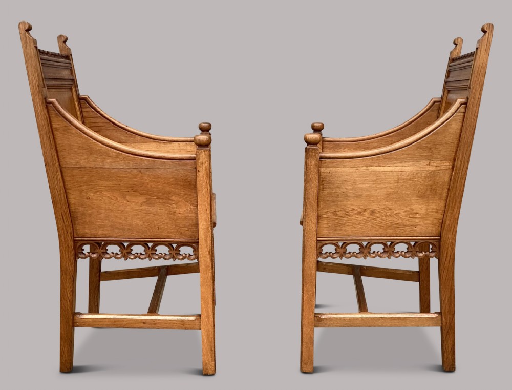 A pair of 19th-century golden oak Gothic Revival armchairs featuring high panelled backrests, shaped arms with spherical terminals, and solid oak seats. View VI