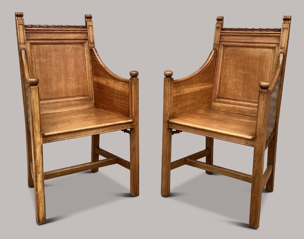 A pair of 19th-century golden oak Gothic Revival armchairs featuring high panelled backrests, shaped arms with spherical terminals, and solid oak seats. View IX