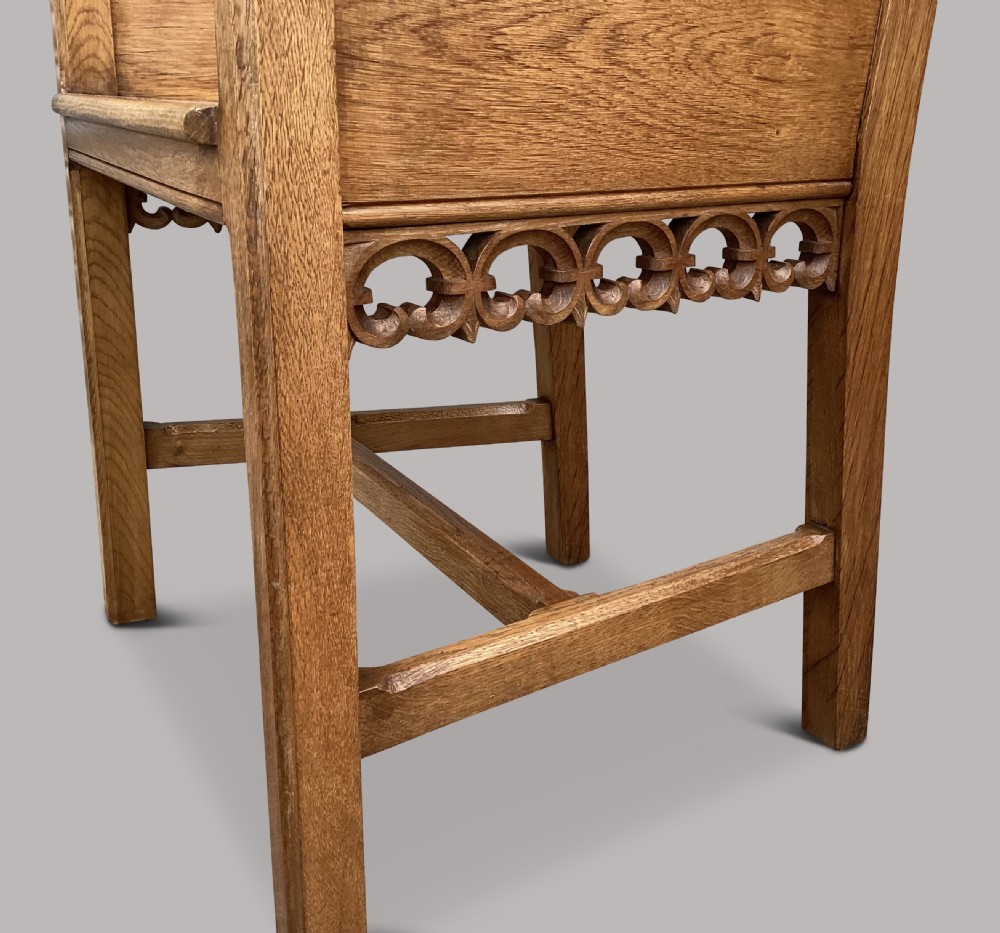 A pair of 19th-century golden oak Gothic Revival armchairs featuring high panelled backrests, shaped arms with spherical terminals, and solid oak seats. View XVIII