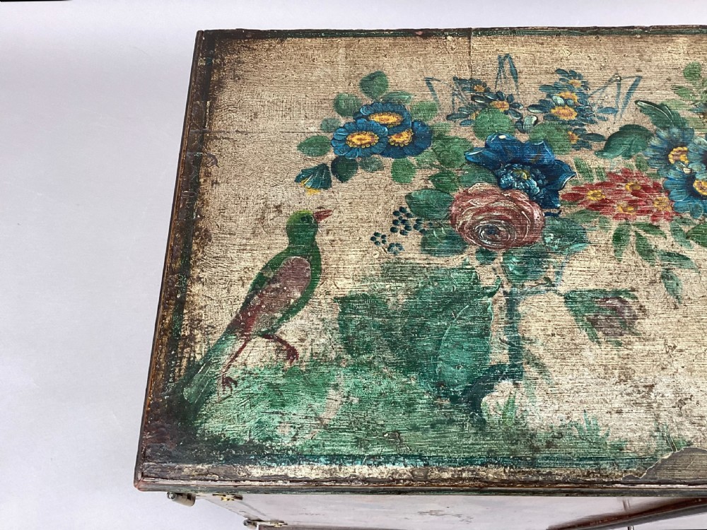 An eighteenth-century hand-painted wooden cabinet on a tall stand, featuring floral artwork across the twin doors, side panels, and apron, mounted with brass hinges. View XII