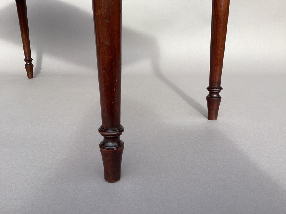 A rectangular George III mahogany window seat featuring sage green velvet upholstery with brass studding, reeded rails, carved corner blocks, and tapered turned legs. View XIV