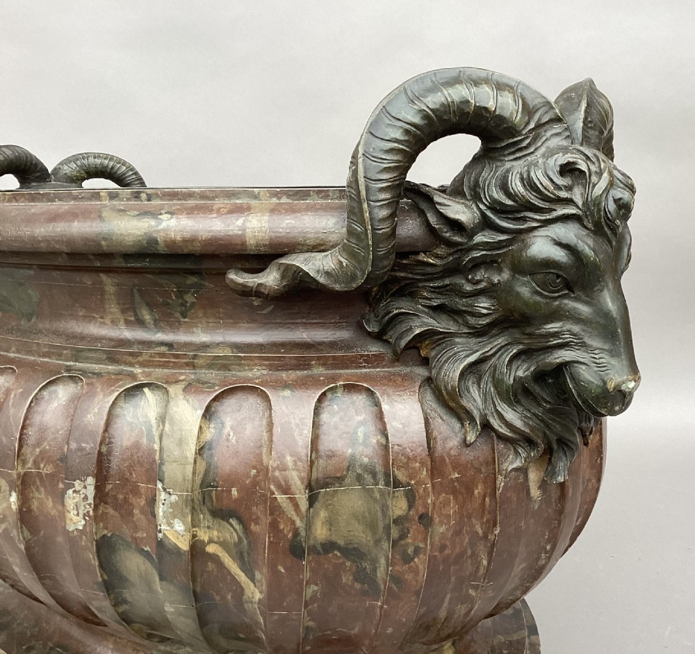A Regency style oval wine cistern featuring a faux marble painted body with fluted decoration, cast bronze ram head handles, and an internal metal liner. View XIV