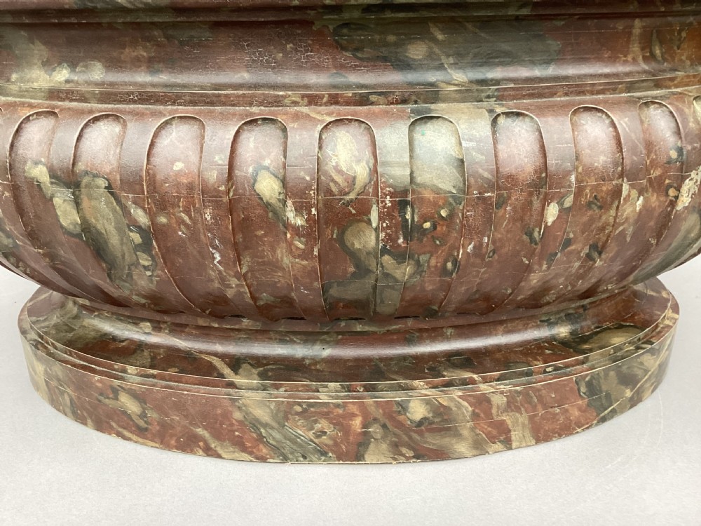 A Regency style oval wine cistern featuring a faux marble painted body with fluted decoration, cast bronze ram head handles, and an internal metal liner. View XXV