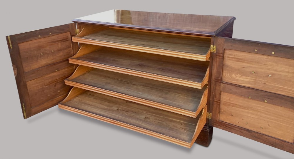 A George III mahogany low press cupboard with doors styled as faux drawers, brass swan-neck handles, bracket feet, and internal sliding shelves. View II