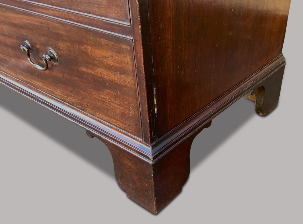 A George III mahogany low press cupboard with doors styled as faux drawers, brass swan-neck handles, bracket feet, and internal sliding shelves. View XIII