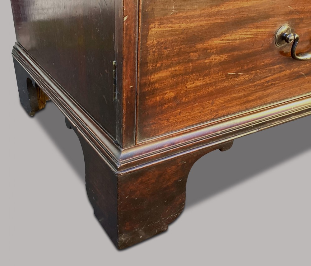 A George III mahogany low press cupboard with doors styled as faux drawers, brass swan-neck handles, bracket feet, and internal sliding shelves. View XIV