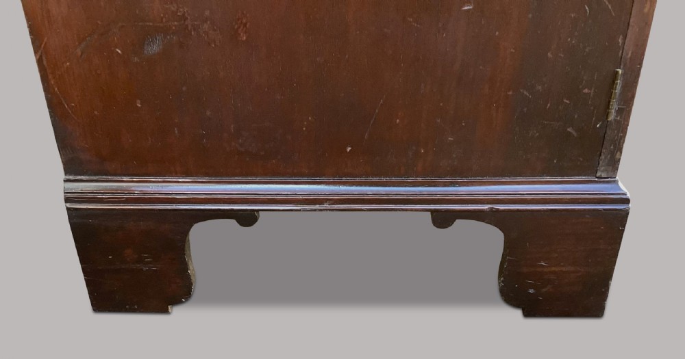 A George III mahogany low press cupboard with doors styled as faux drawers, brass swan-neck handles, bracket feet, and internal sliding shelves. View XVIII