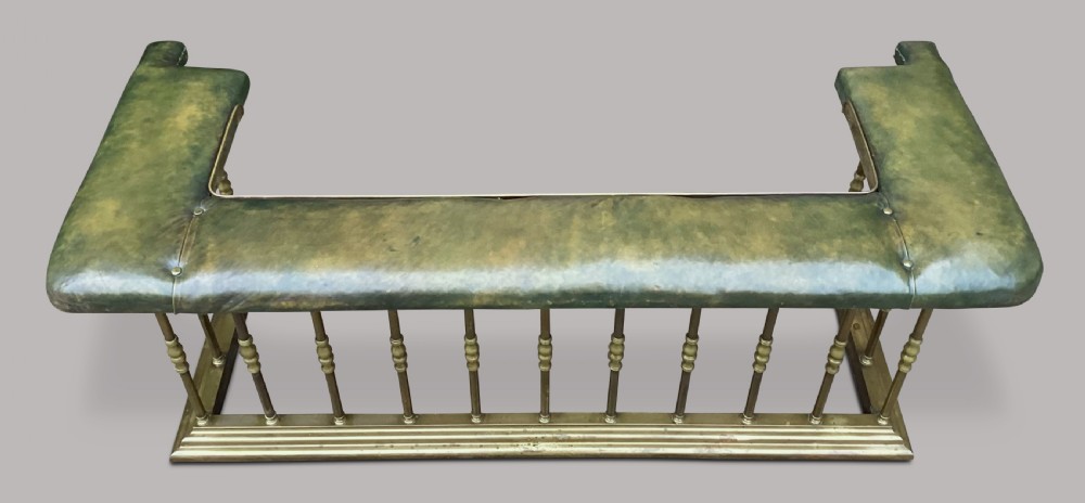A nineteenth-century brass club fender featuring turned baluster uprights and a continuous U-shaped green leather upholstered seat cushion. View III