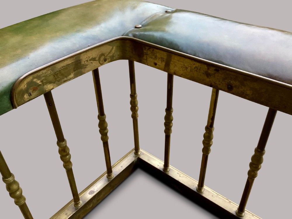A nineteenth-century brass club fender featuring turned baluster uprights and a continuous U-shaped green leather upholstered seat cushion. View VII