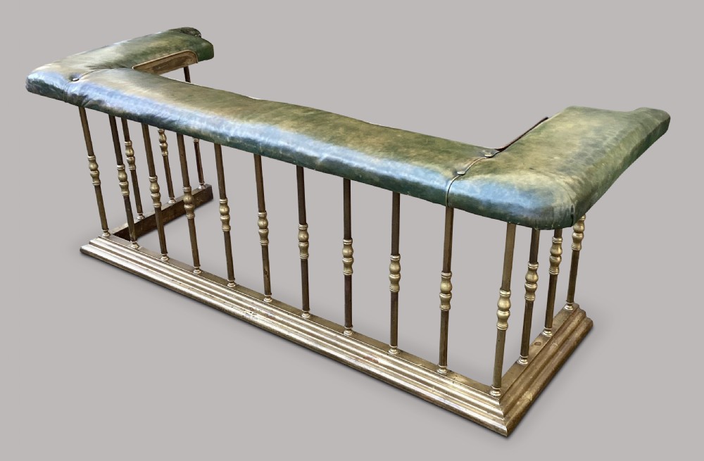 A nineteenth-century brass club fender featuring turned baluster uprights and a continuous U-shaped green leather upholstered seat cushion. View XII