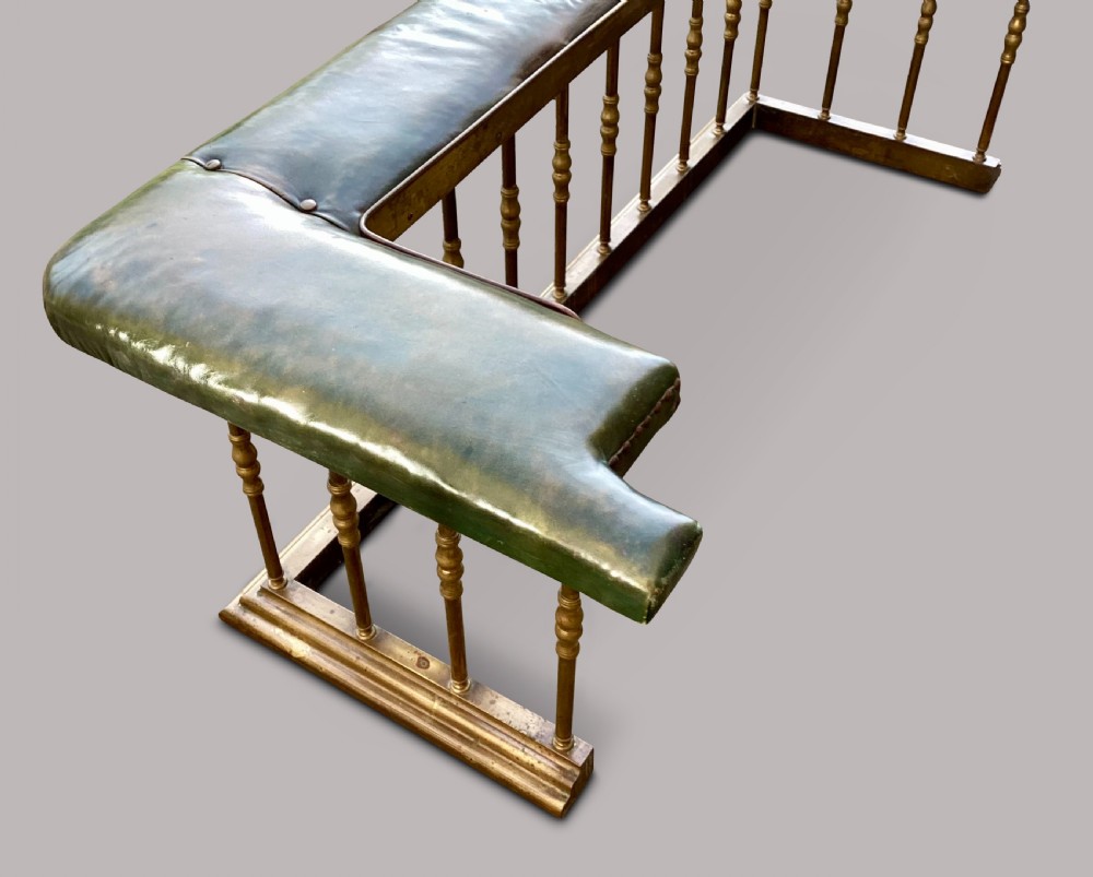 A nineteenth-century brass club fender featuring turned baluster uprights and a continuous U-shaped green leather upholstered seat cushion. View XIV