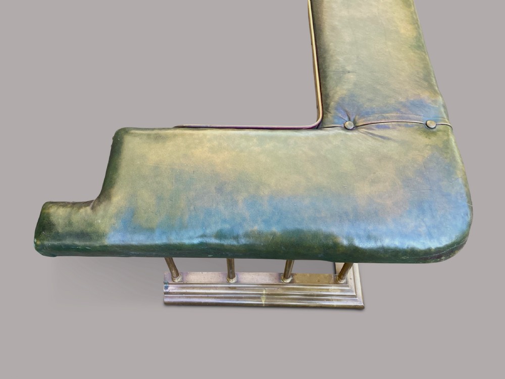 A nineteenth-century brass club fender featuring turned baluster uprights and a continuous U-shaped green leather upholstered seat cushion. View XVII