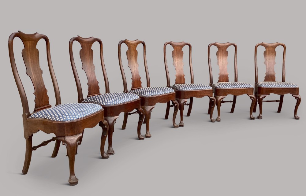 A set of six George II red walnut side dining chairs with shaped vasiform splats, cabriole front legs, and blue patterned drop-in seats.