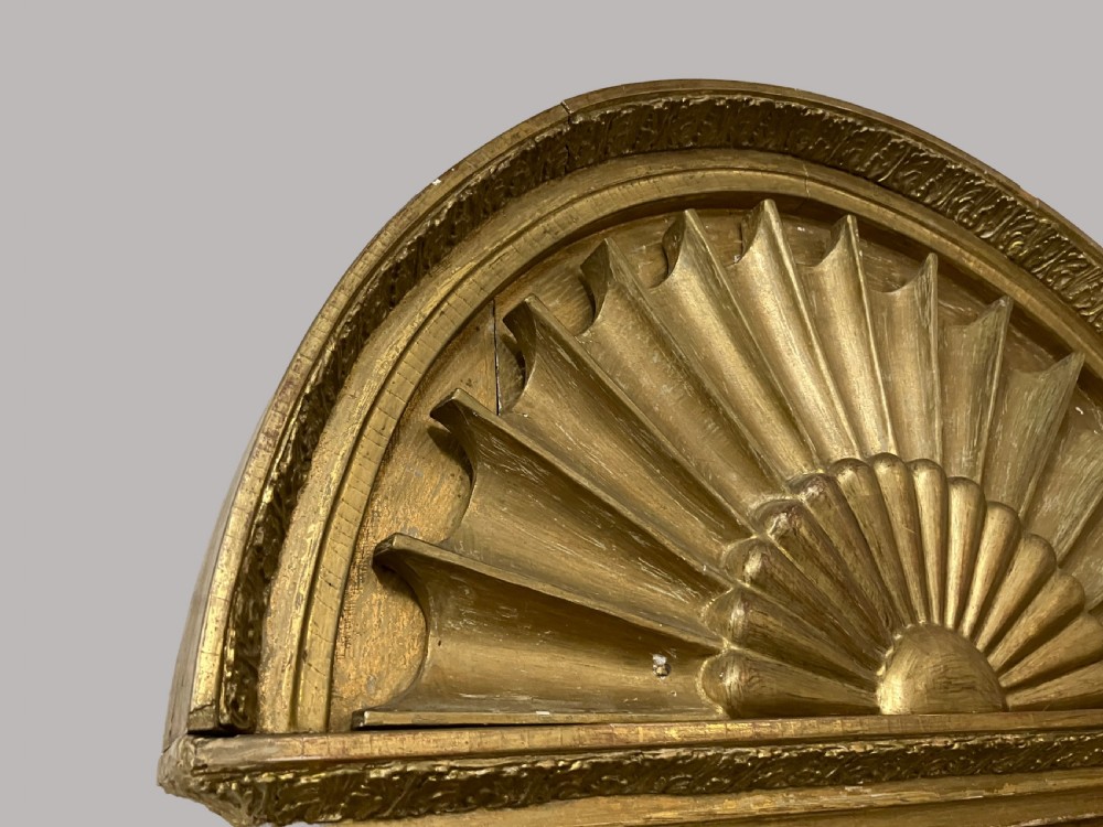 A nineteenth-century Swedish giltwood wall mirror featuring an arched lunette top with carved sunburst detailing and fluted side pilasters. View V