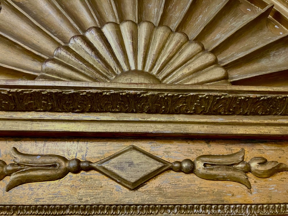 A nineteenth-century Swedish giltwood wall mirror featuring an arched lunette top with carved sunburst detailing and fluted side pilasters. View VII