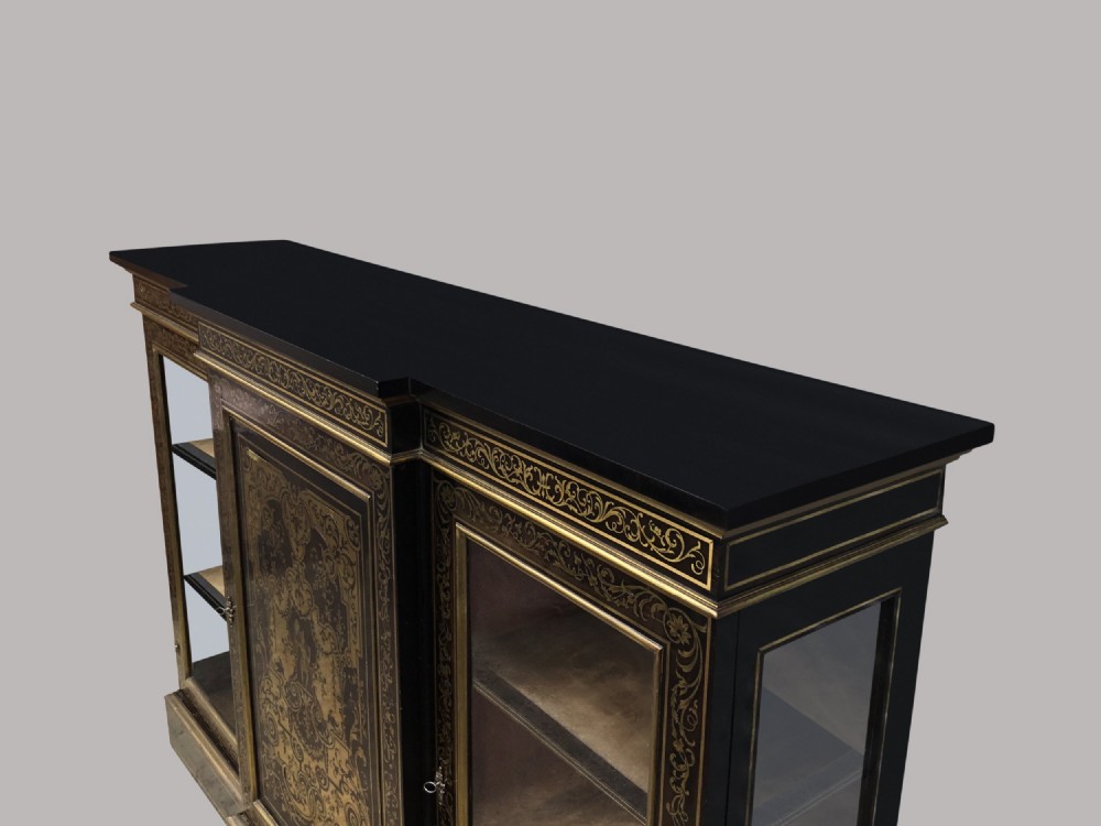 A 19th-century ebony breakfront side cabinet featuring central Boulle brass marquetry door panels flanked by two glazed display cabinet doors. View IX