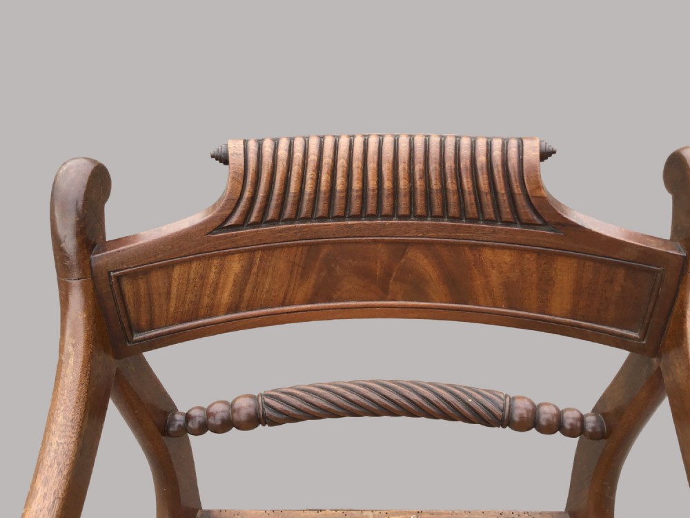 A set of six Regency mahogany open armchairs featuring woven cane seats, curved scroll arms, reeded top rails, and sabre legs. View III