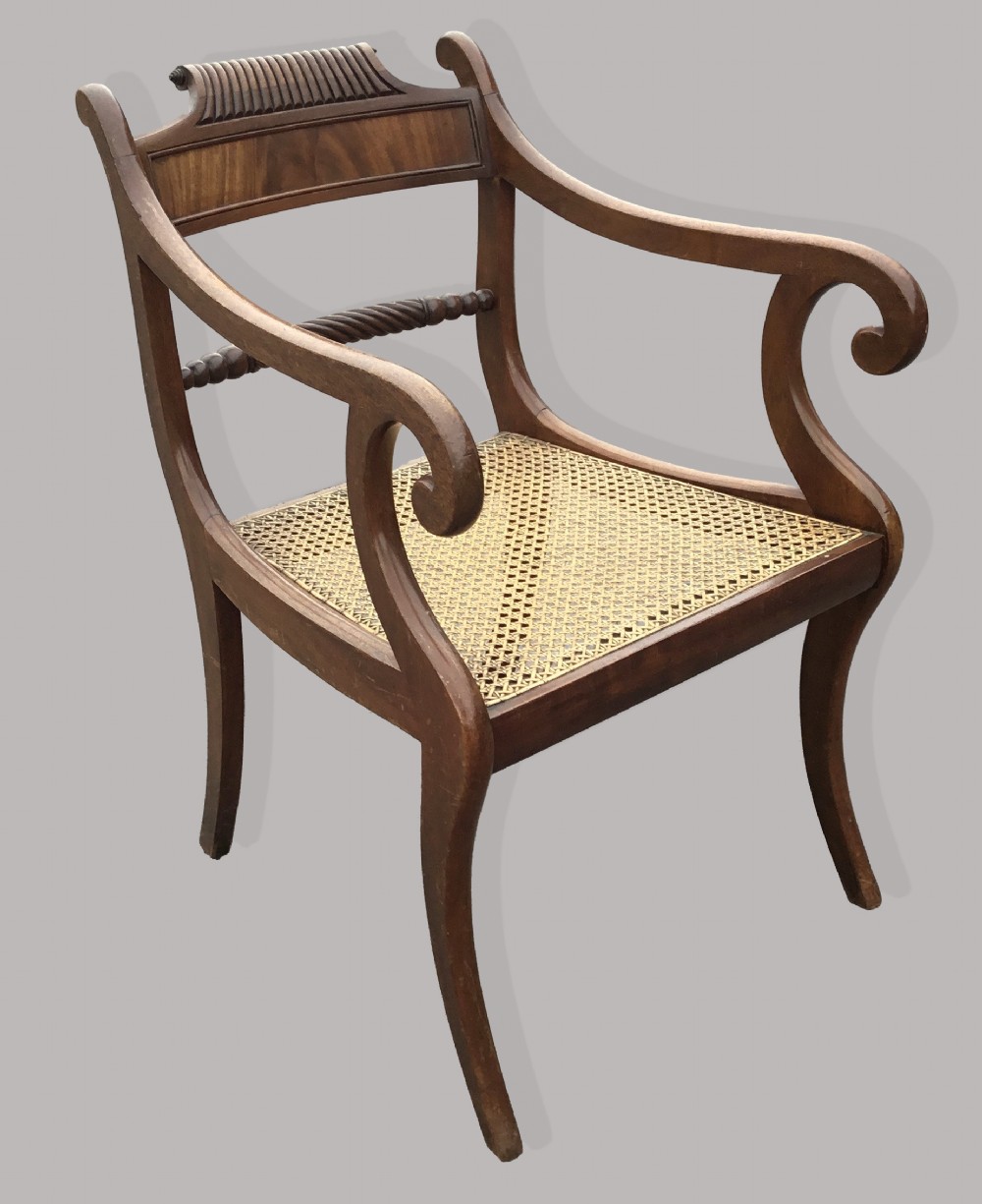 A set of six Regency mahogany open armchairs featuring woven cane seats, curved scroll arms, reeded top rails, and sabre legs. View V