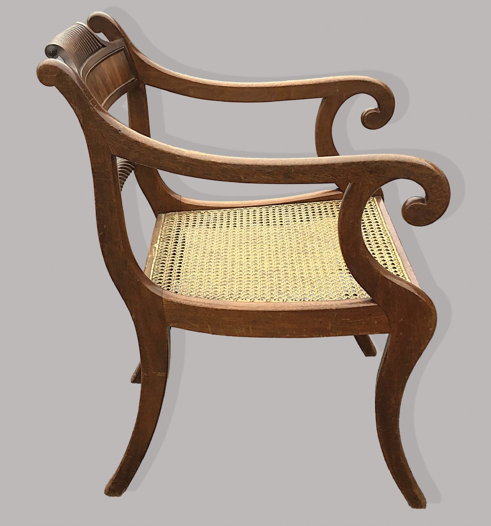 A set of six Regency mahogany open armchairs featuring woven cane seats, curved scroll arms, reeded top rails, and sabre legs. View VI