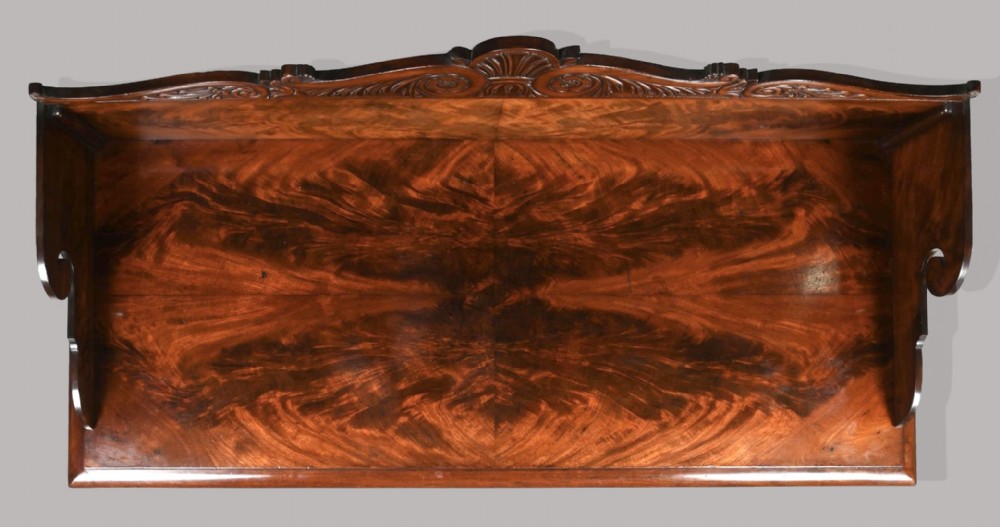 A Regency mahogany console table featuring a carved scroll cresting backboard, flame mahogany veneers, carved acanthus leaf legs, and paw feet on a plinth base. View XIV
