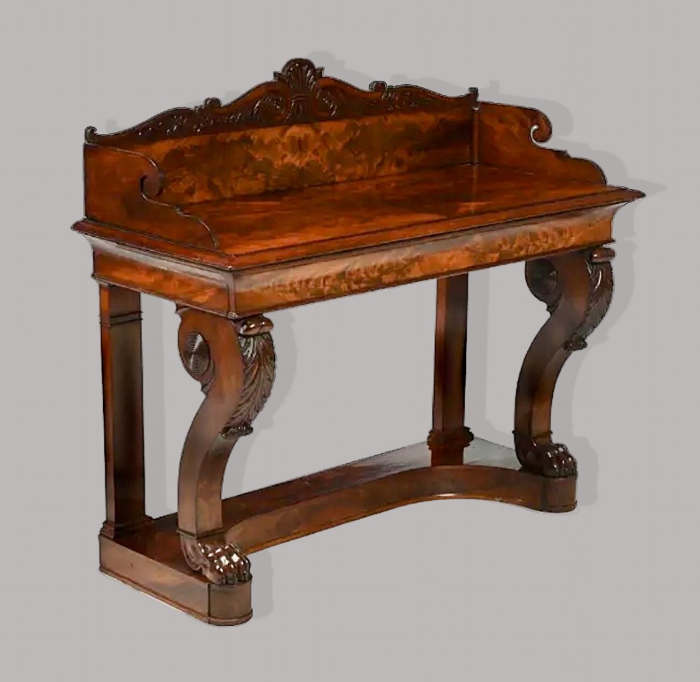 A Regency mahogany console table featuring a carved scroll cresting backboard, flame mahogany veneers, carved acanthus leaf legs, and paw feet on a plinth base. View XV