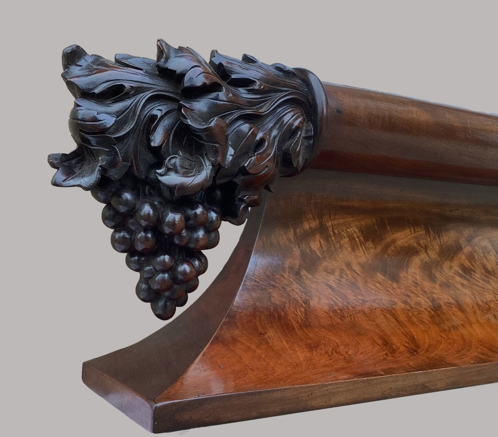 A long George IV figured mahogany pelmet featuring carved acanthus leaves and grape cluster finials at either end. View III