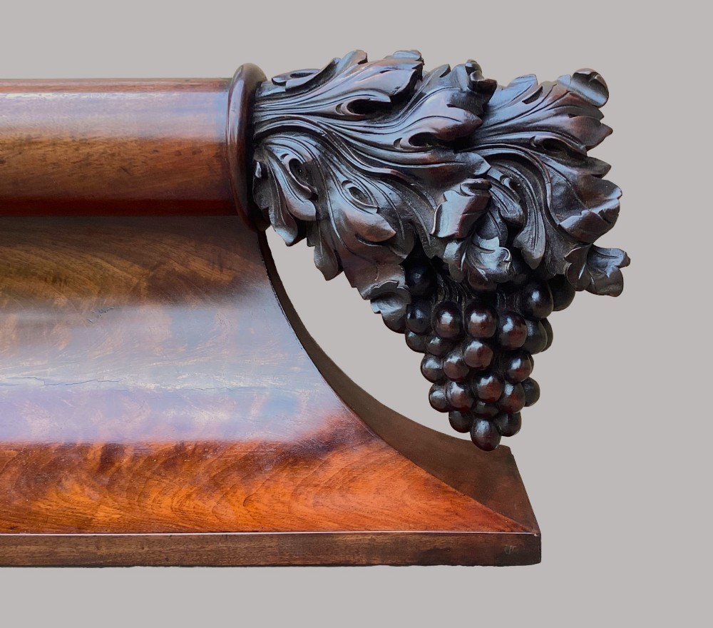 A long George IV figured mahogany pelmet featuring carved acanthus leaves and grape cluster finials at either end. View IV