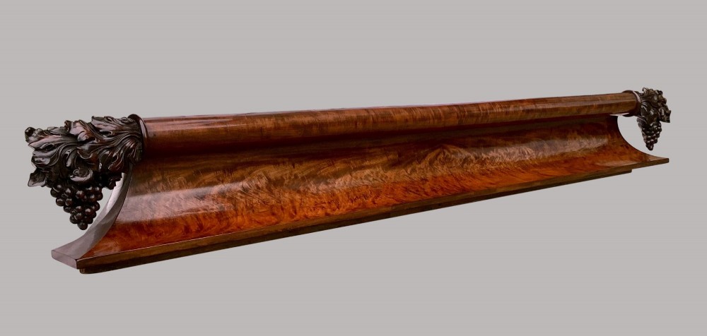 A long George IV figured mahogany pelmet featuring carved acanthus leaves and grape cluster finials at either end. View V