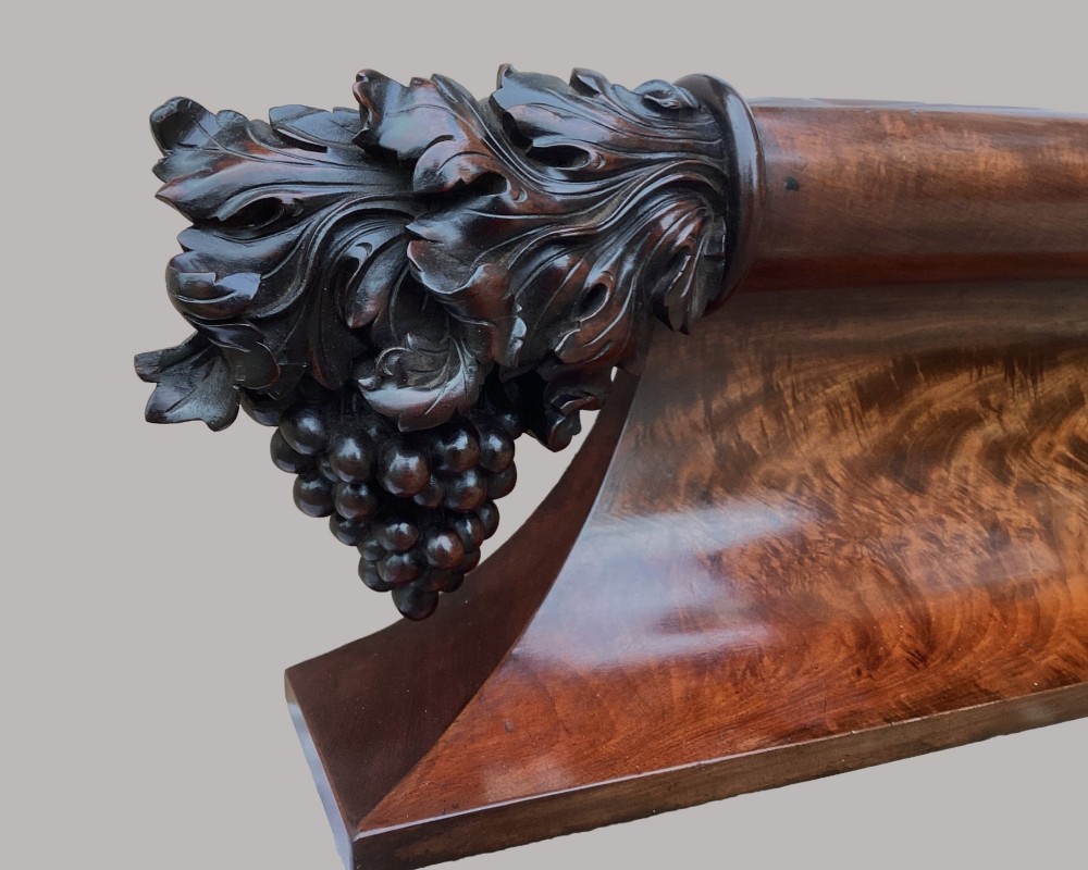 A long George IV figured mahogany pelmet featuring carved acanthus leaves and grape cluster finials at either end. View VIII