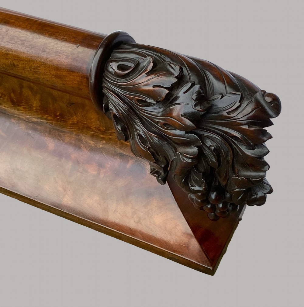 A long George IV figured mahogany pelmet featuring carved acanthus leaves and grape cluster finials at either end. View IX