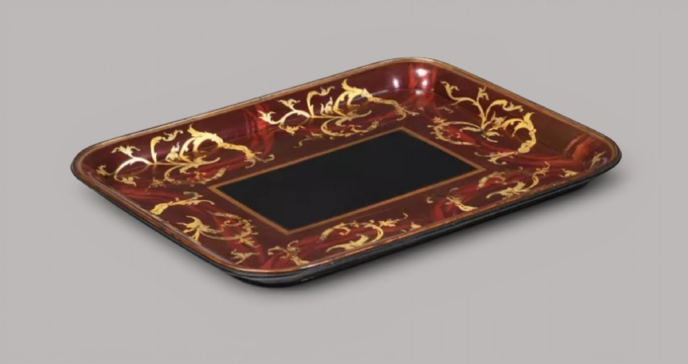 A rectangular Regency papier-mache tray with rounded edges, featuring gilded foliage and red swirl decoration surrounding a central black panel. View II